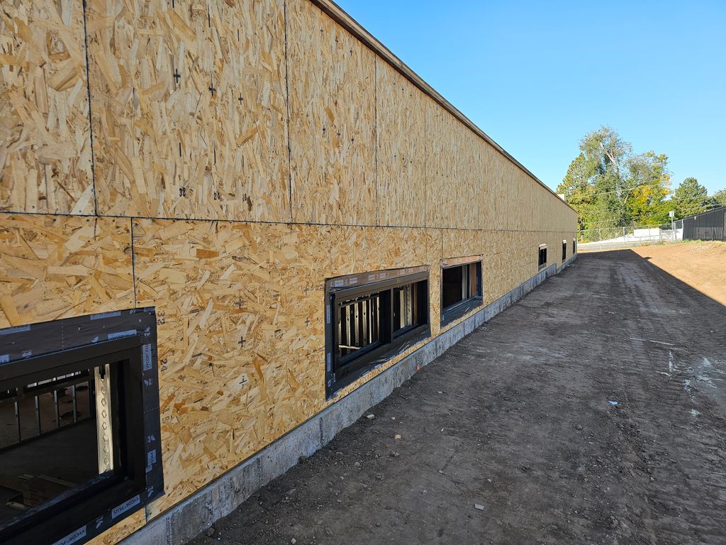 Exterior view showing the sloped grade rising to the window line against the retaining wall of a Layton, Utah office building.