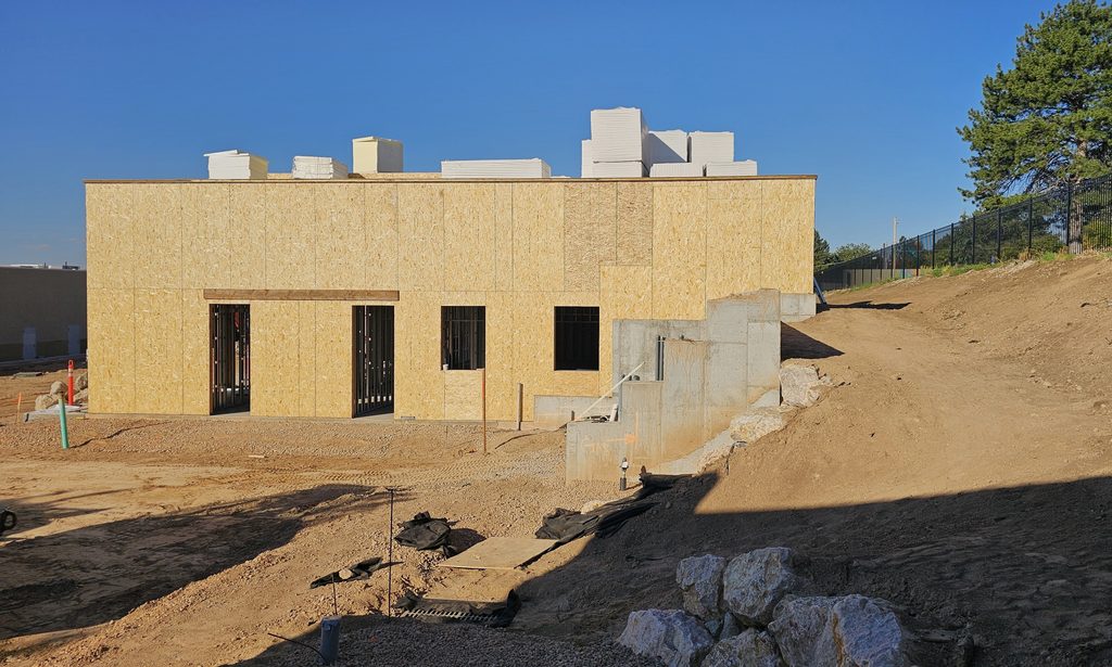 Concrete retaining wall supporting a new office building on a sloped lot in Layton, Utah.