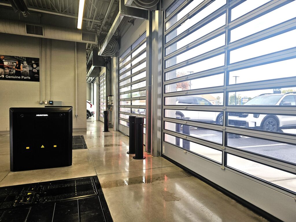 Service drive at Young Kia Layton with full-view glass overhead doors, bollards and air curtains